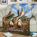 Rustic goat throw blanket displayed on a sofa with a pastoral farm landscape, brick wall, and colorful flowers