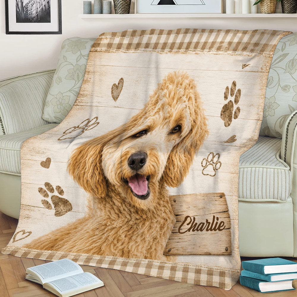 Close view of a Labradoodle throw blanket featuring a happy curly dog, rustic wood design, paw prints, and plaid trim