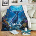 Mermaid throw blanket draped over a sofa with a blue underwater tail and colorful coral reef artwork