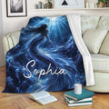 Mermaid throw blanket draped over a sofa with deep blue underwater artwork, sea life, bubbles, and radiant light rays