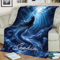 Blue mermaid throw blanket displayed on a couch with an underwater fantasy scene and flowing tail artwork