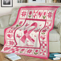 Pink ribbon breast cancer blanket draped over a couch with butterflies, flowers, and heart motifs