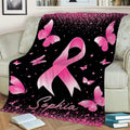 Pink ribbon breast cancer awareness blanket draped over a couch with butterfly artwork