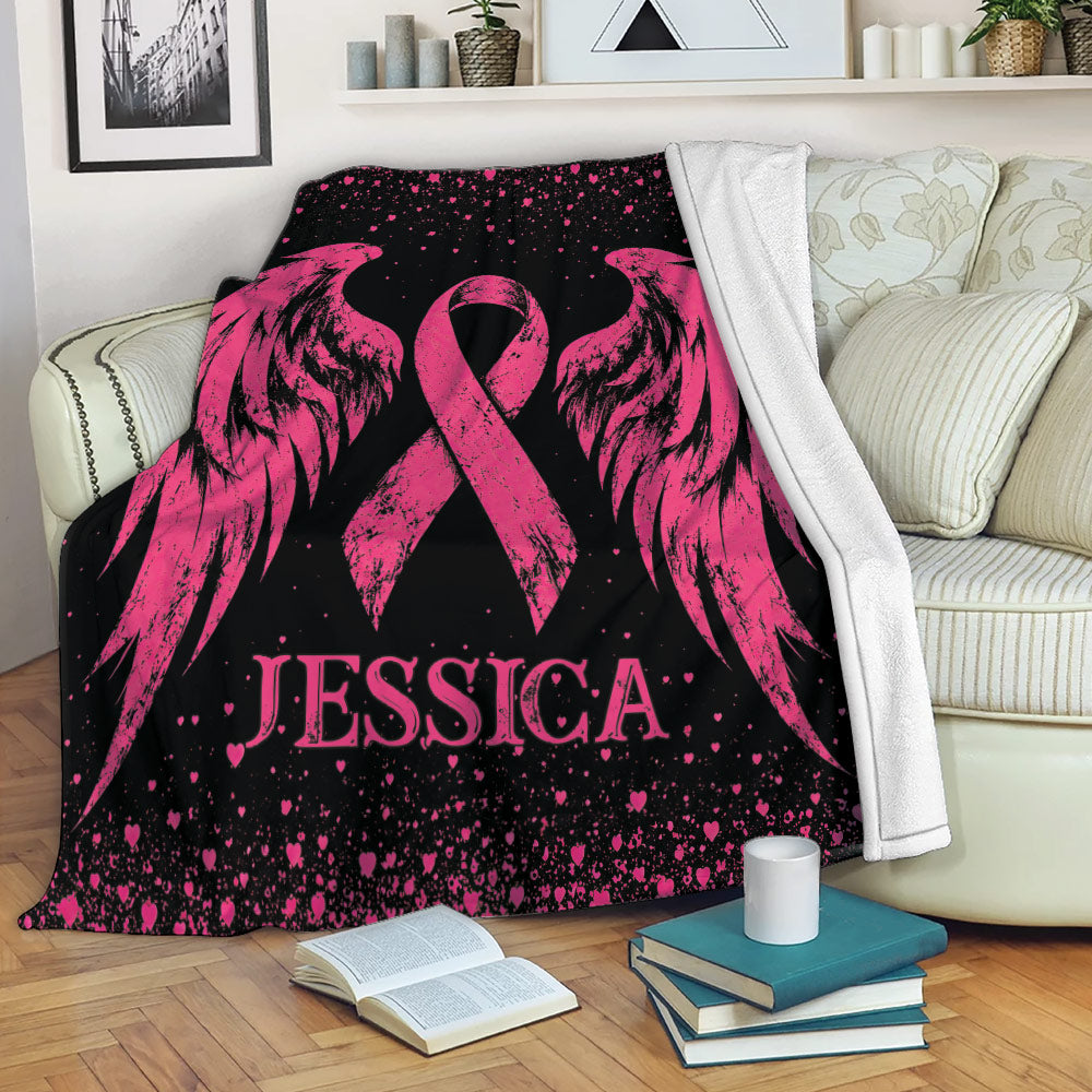 Pink breast cancer ribbon wing blanket draped over a sofa in a cozy living room