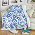 Blue diabetes awareness throw blanket with floral ribbons draped across a living room sofa