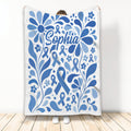 Blue diabetes awareness ribbon blanket with floral artwork shown held up against a light background