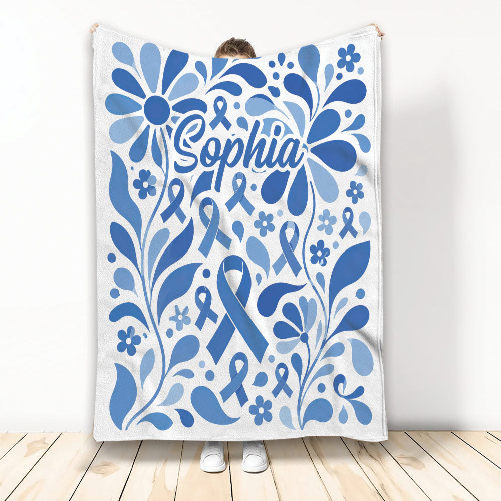 Blue diabetes awareness ribbon blanket with floral artwork shown held up against a light background