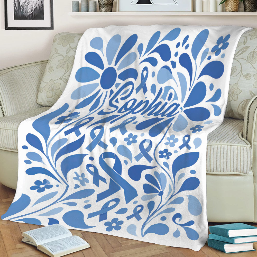 Blue ribbon diabetes awareness blanket displayed over a sofa with decorative floral artwork