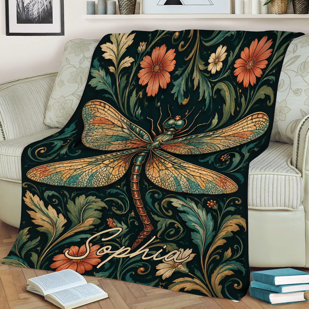Decorative dragonfly blanket displayed on a couch with vintage-inspired flowers and foliage