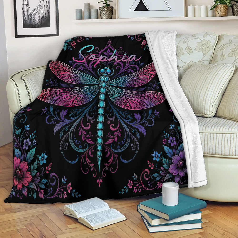 Dragonfly blanket draped over a sofa with vibrant pink, purple, and blue floral artwork
