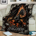 Black dragon throw blanket featuring wings, flames, and rocky fantasy artwork on a sofa