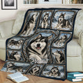 Close lifestyle view of an Alaskan Malamute throw blanket covering a sofa with snowy woodland artwork