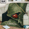 Ladybug throw blanket displayed on a sofa with detailed green leaf and nature artwork