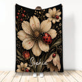 Ladybug throw blanket with large cream flowers, red ladybugs, botanical accents, and dark floral artwork