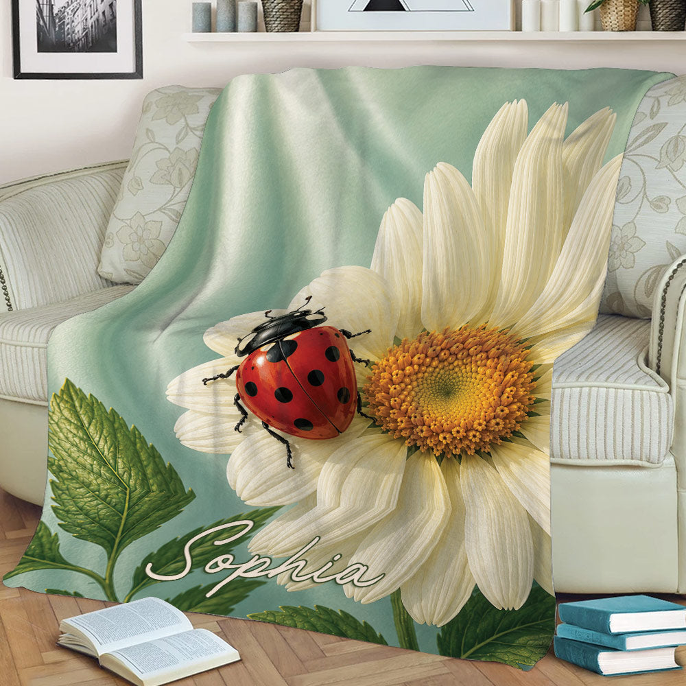 Floral ladybug throw blanket displayed on a couch with a red beetle, white flower and leafy design