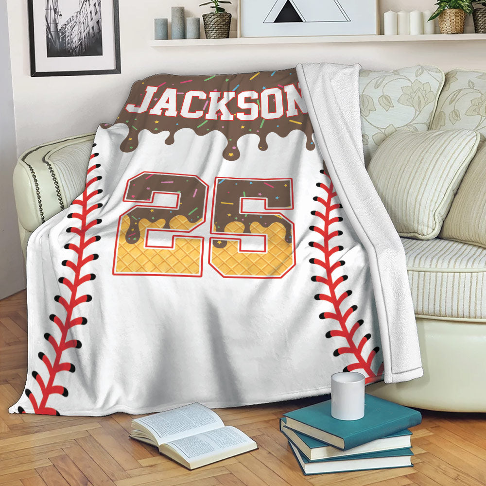 Baseball blanket draped over a sofa with colorful baseball artwork, seam borders, and a bold jersey-inspired center design