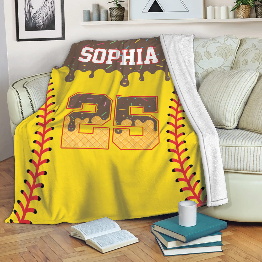 Softball throw blanket draped over a sofa with bright yellow, maroon, and purple sports artwork