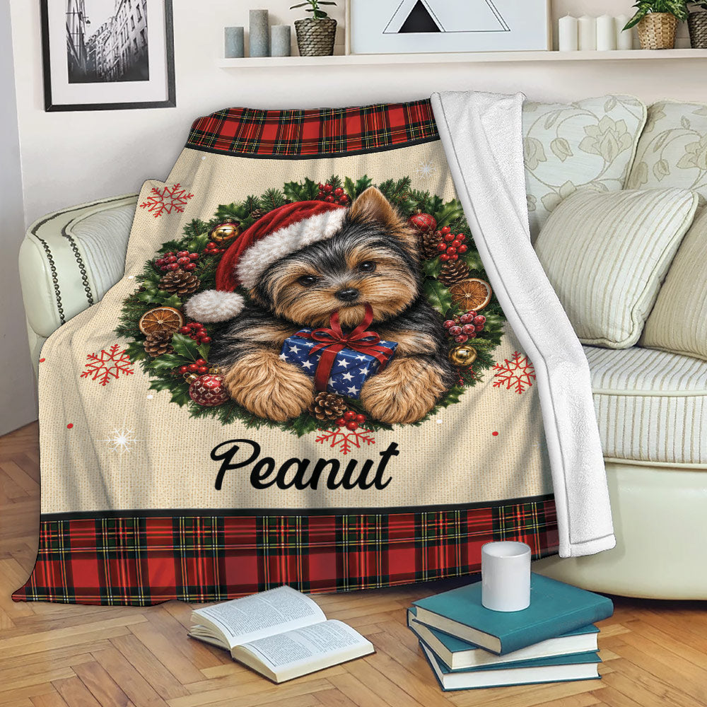 Yorkie holiday throw blanket draped over a sofa with wreath artwork, wrapped gift and red plaid border