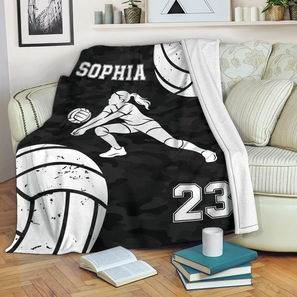 Volleyball throw blanket draped over a couch with a female player design and black camouflage background