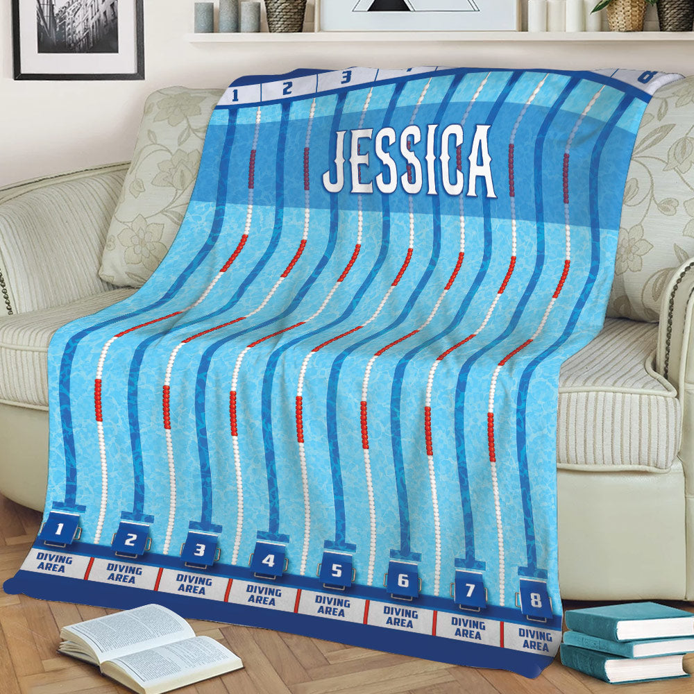 Blue swimming throw blanket spread across a sofa with numbered pool lanes and diving areas