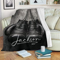 Custom boxing throw blanket with black gloves draped over a sofa in a cozy living room