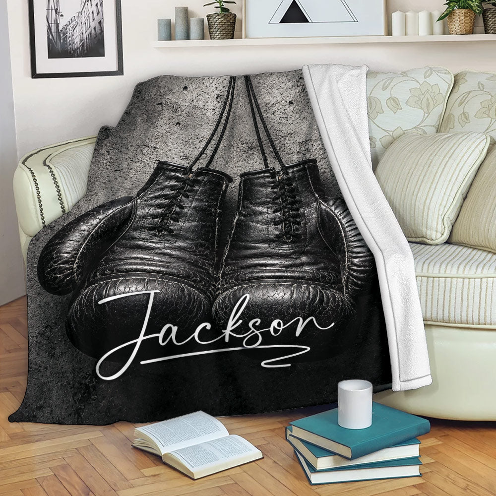 Custom boxing throw blanket with black gloves draped over a sofa in a cozy living room