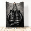 Black boxing gloves displayed on a textured dark background on a custom boxing throw blanket