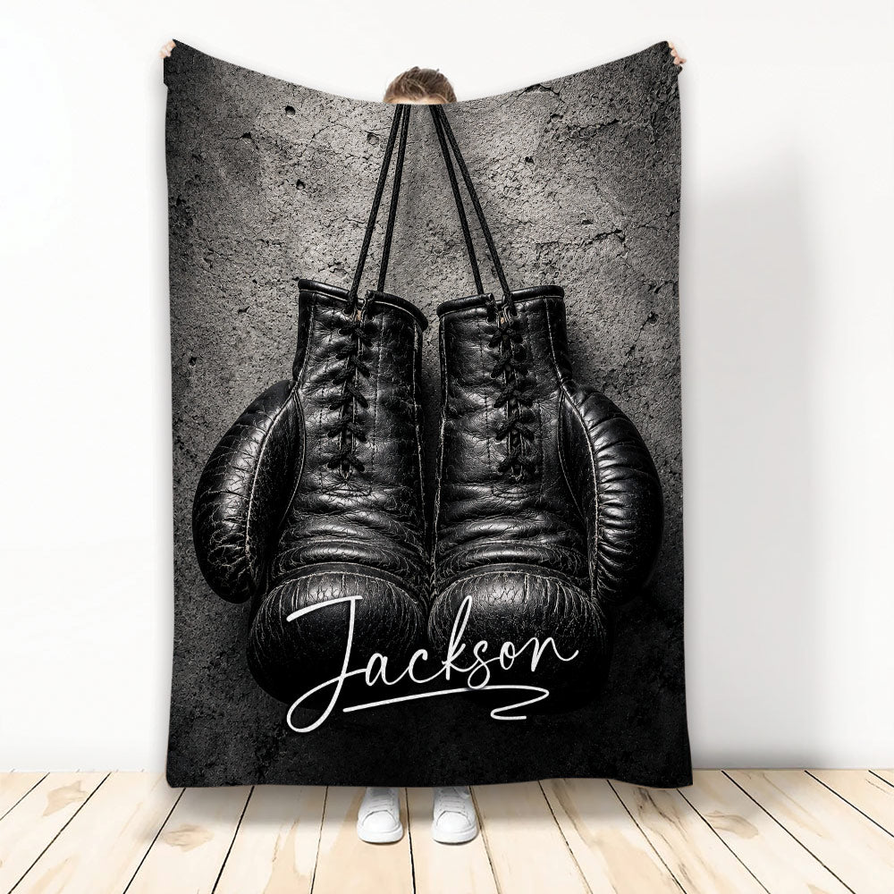 Black boxing gloves displayed on a textured dark background on a custom boxing throw blanket