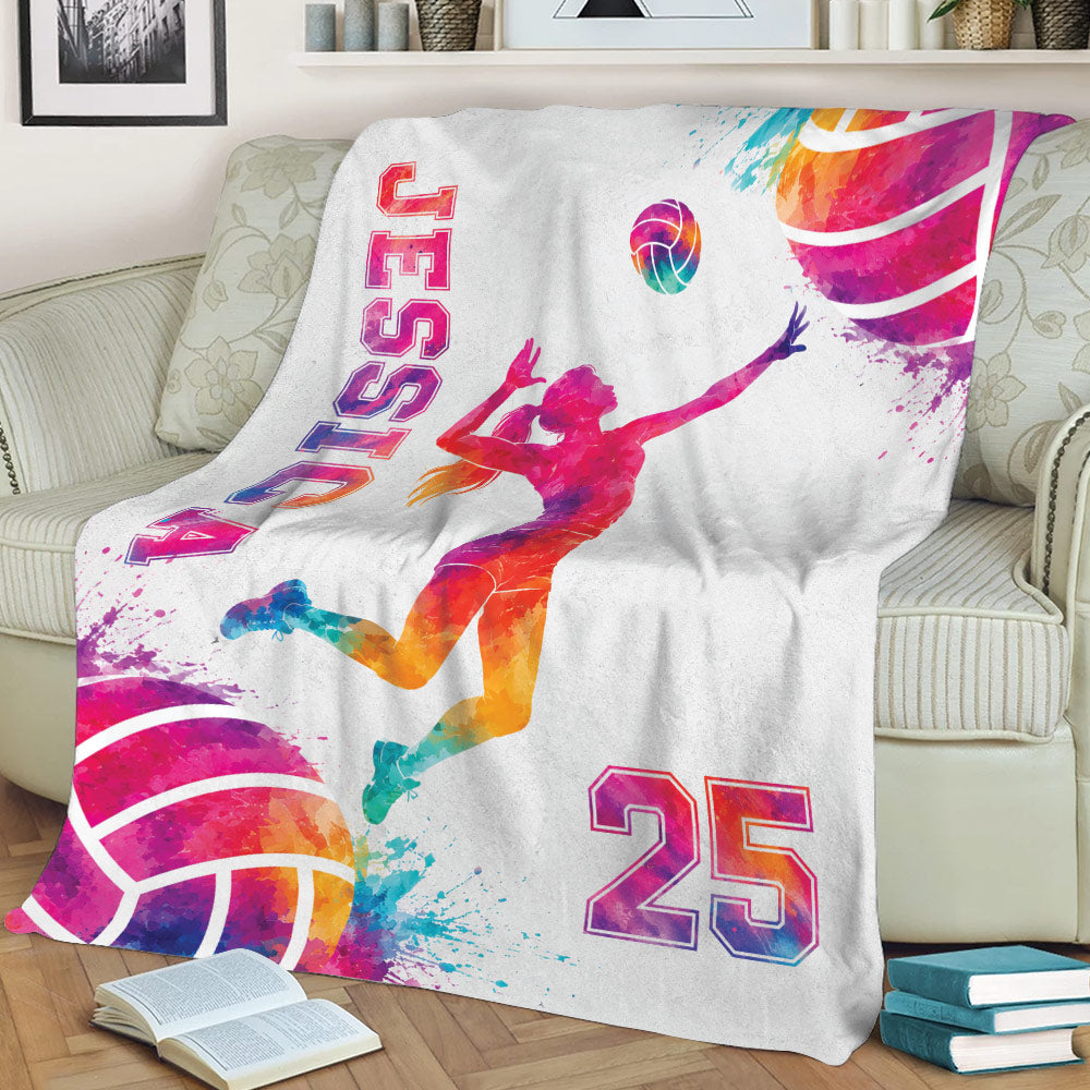 Vibrant volleyball blanket displayed on a couch with female athlete artwork and colorful sports splashes