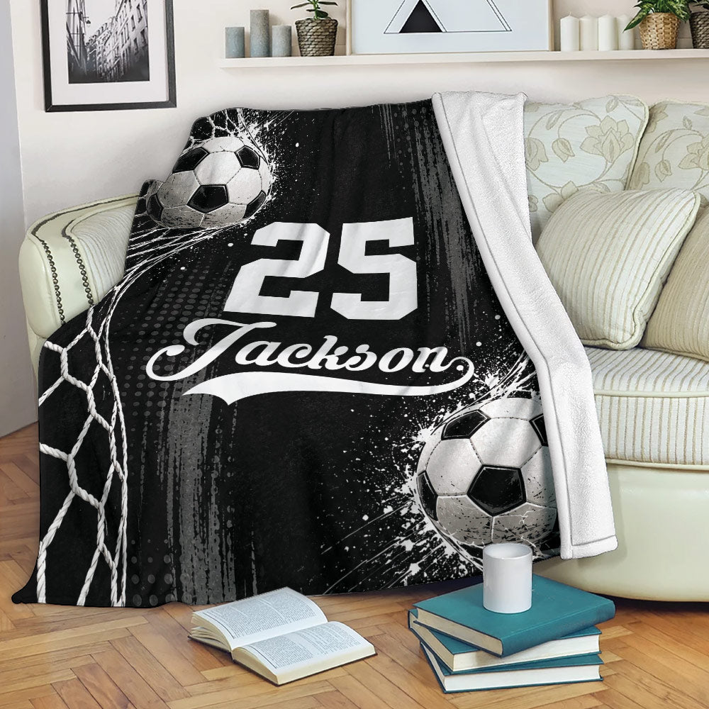 Black and white soccer blanket draped over a sofa with bold sports artwork