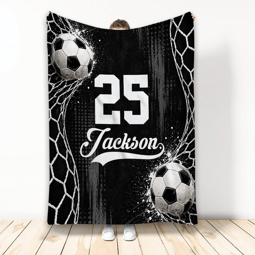 Black and white soccer blanket displayed vertically with soccer balls and goal net artwork