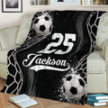 Black and white soccer throw blanket styled across a couch with soccer ball graphics