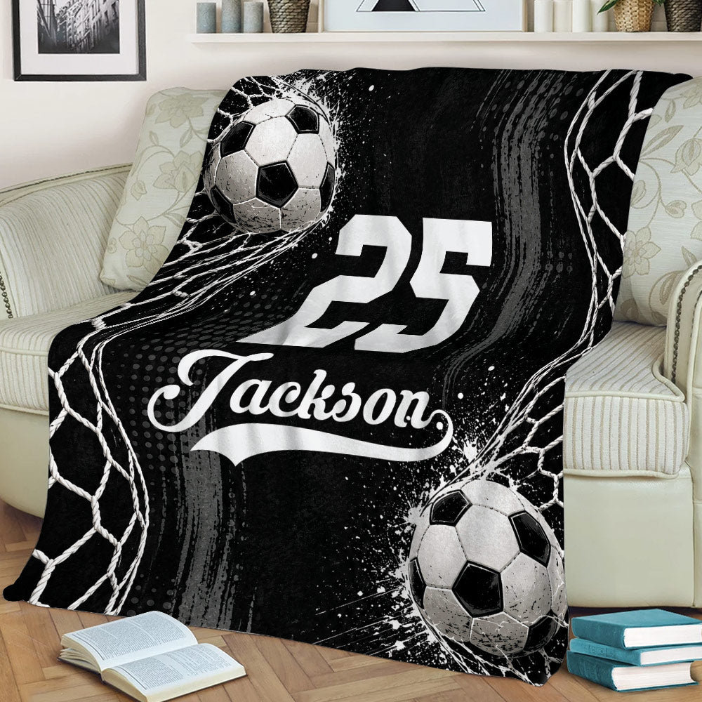 Black and white soccer throw blanket styled across a couch with soccer ball graphics