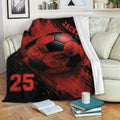 Red and black soccer blanket draped over a sofa with large soccer ball artwork and bold sports graphics