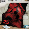Red and black soccer throw blanket styled on an armchair with oversized soccer ball artwork