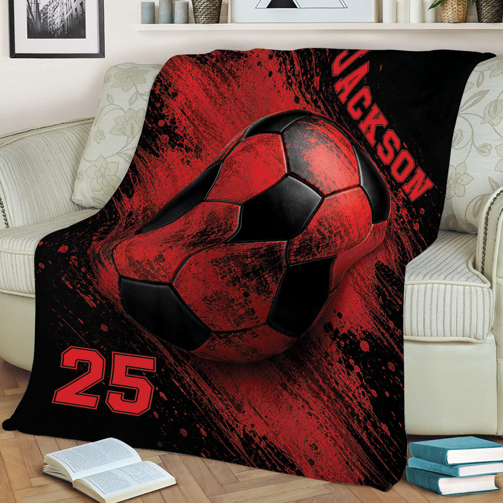 Red and black soccer throw blanket styled on an armchair with oversized soccer ball artwork