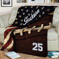 Patriotic football throw blanket displayed on a sofa with stars, stripes, and vintage sports artwork