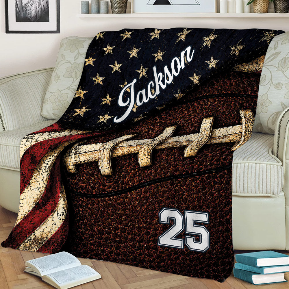 Patriotic football throw blanket displayed on a sofa with stars, stripes, and vintage sports artwork