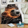 Soccer throw blanket displayed on a sofa with bold black, white, and orange goal artwork