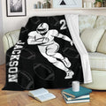 Football throw blanket displayed on a sofa with bold player artwork and black sports design