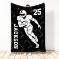 Black football blanket featuring a running player illustration and repeating football pattern