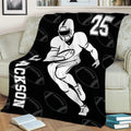 Black football blanket draped over a couch with running player artwork and football pattern