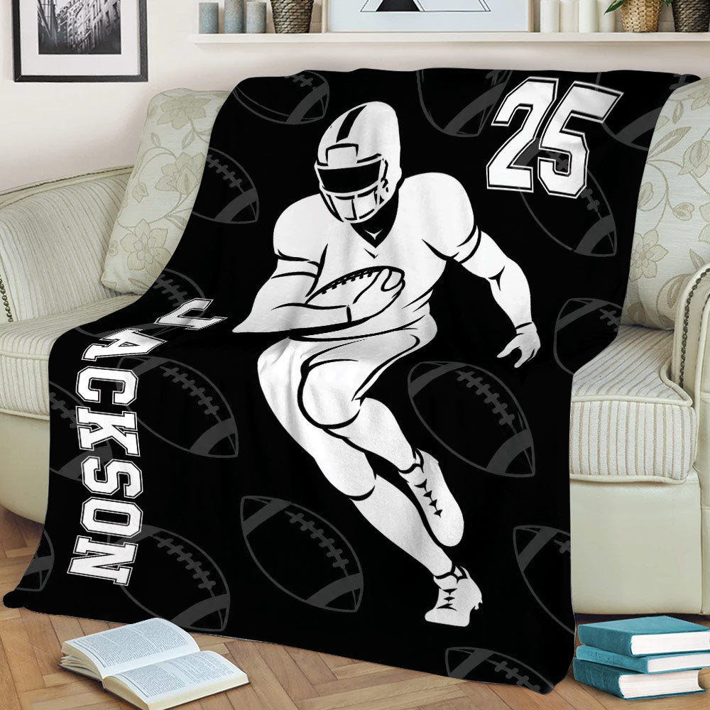 Black football blanket draped over a couch with running player artwork and football pattern