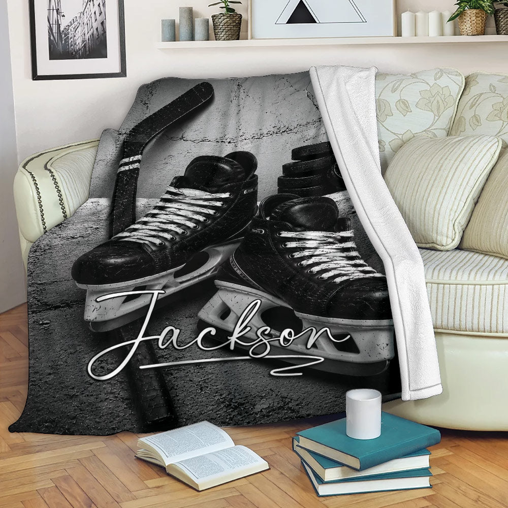 Hockey throw blanket displayed on a sofa with skates, stick, and puck artwork