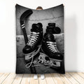 Black and white hockey blanket featuring ice skates, hockey stick, and stacked pucks