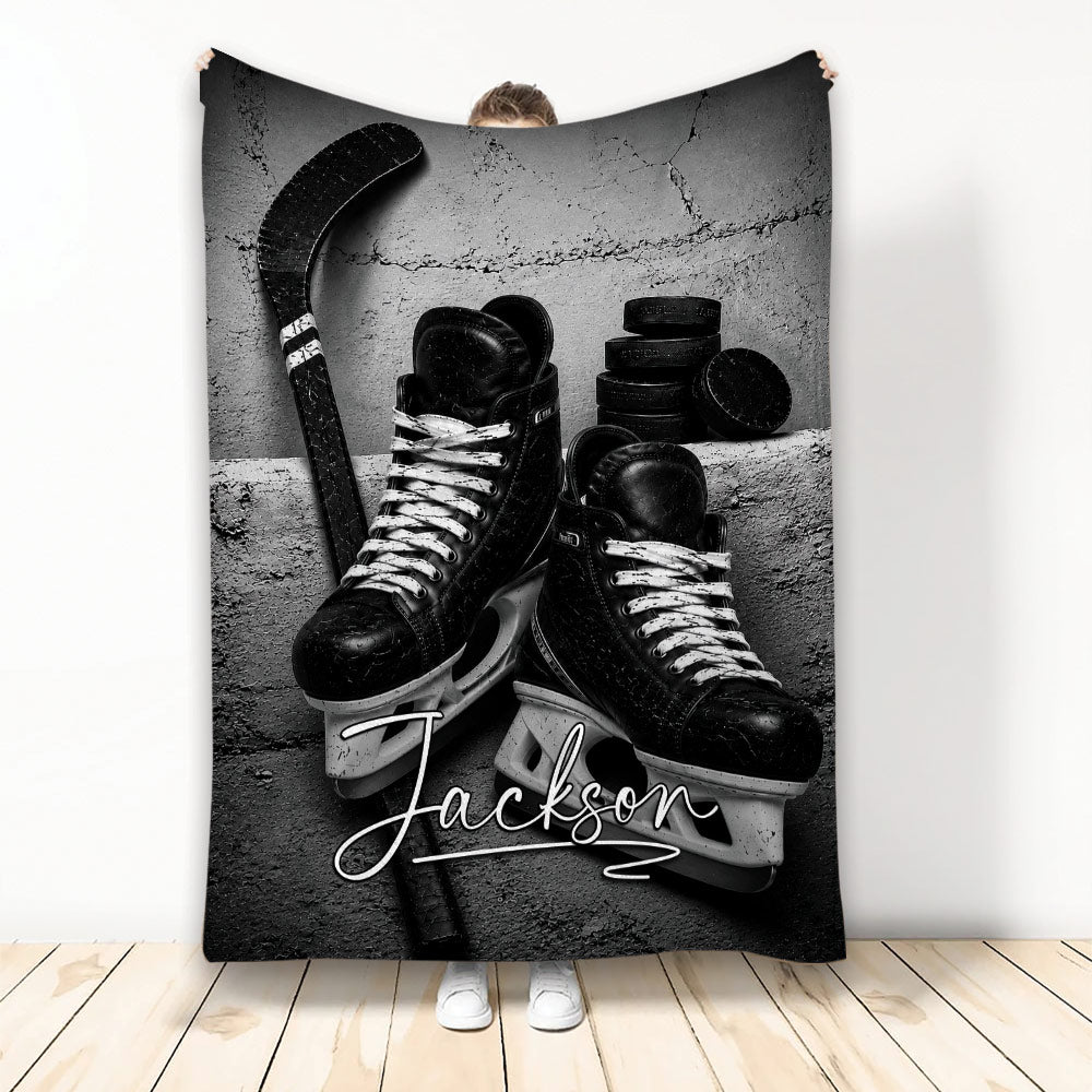 Black and white hockey blanket featuring ice skates, hockey stick, and stacked pucks