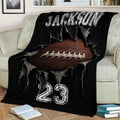 Black football blanket draped over a sofa, featuring a close-up football bursting through ripped fabric