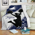 Cheerleading blanket draped over a sofa, featuring a cheerleader silhouette and navy blue pom-pom design