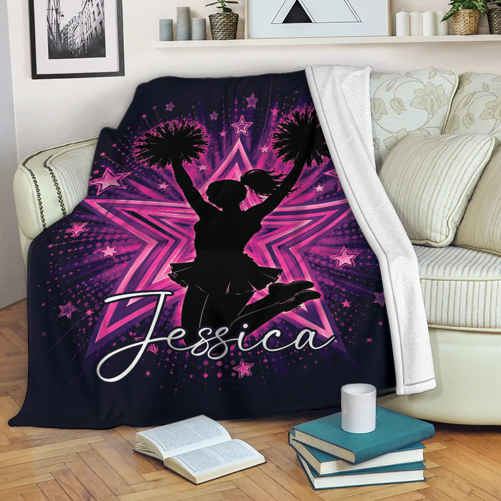 Cheerleading blanket displayed on a sofa with a vibrant pink starburst and cheerleader silhouette design