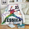 Softball throw blanket draped over a couch with colorful female player artwork and softball-themed splatter design